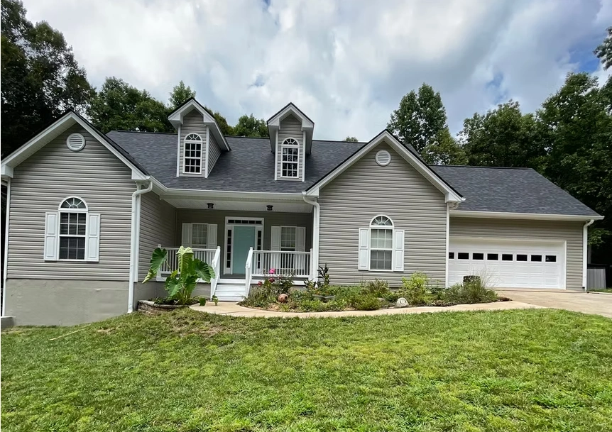 A multi-gabled house in Alpharetta, GA, showcasing common exterior painting services with its light gray horizontal siding, crisp white shutters, white trim, and a pale blue accent front door.