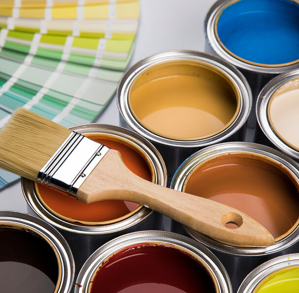 High Quality Paint Finishes. A wooden paintbrush rests on open cans of various paint colors, including blue, yellow, and brown. A green color palette fan is partially visible.