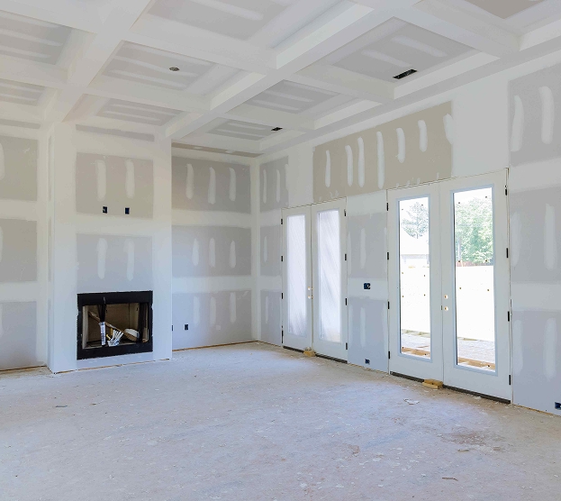 Unfinished room with drywall in progress, featuring a black fireplace, coffered ceiling, and double glass doors leading outside. Bright and spacious.