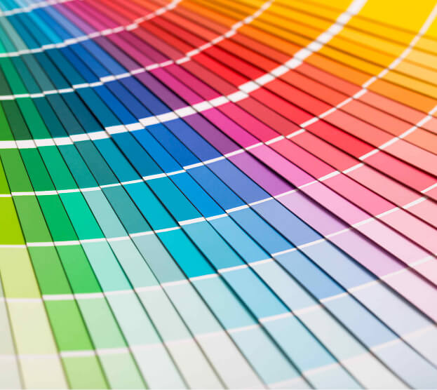 A vibrant array of colorful paint swatches forms a dynamic, sweeping arc. The spectrum transitions smoothly from greens to blues, purples, and reds.