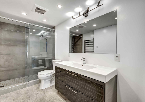 Modern bathroom with sleek design. Features large mirror, rectangular sink on dark wood cabinet, glass-enclosed shower, and recessed lighting.