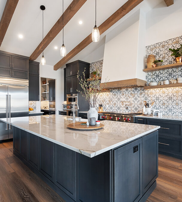 Bright kitchen with wooden beams and modern fixtures. Features a large marble island, dark cabinets, patterned backsplash, and warm lighting. Cozy yet elegant.